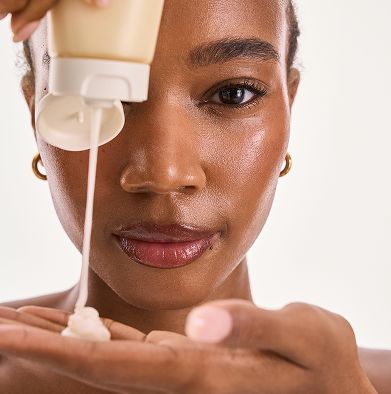 Close up of woman dispensing moisturizer into palm for skincare routine.